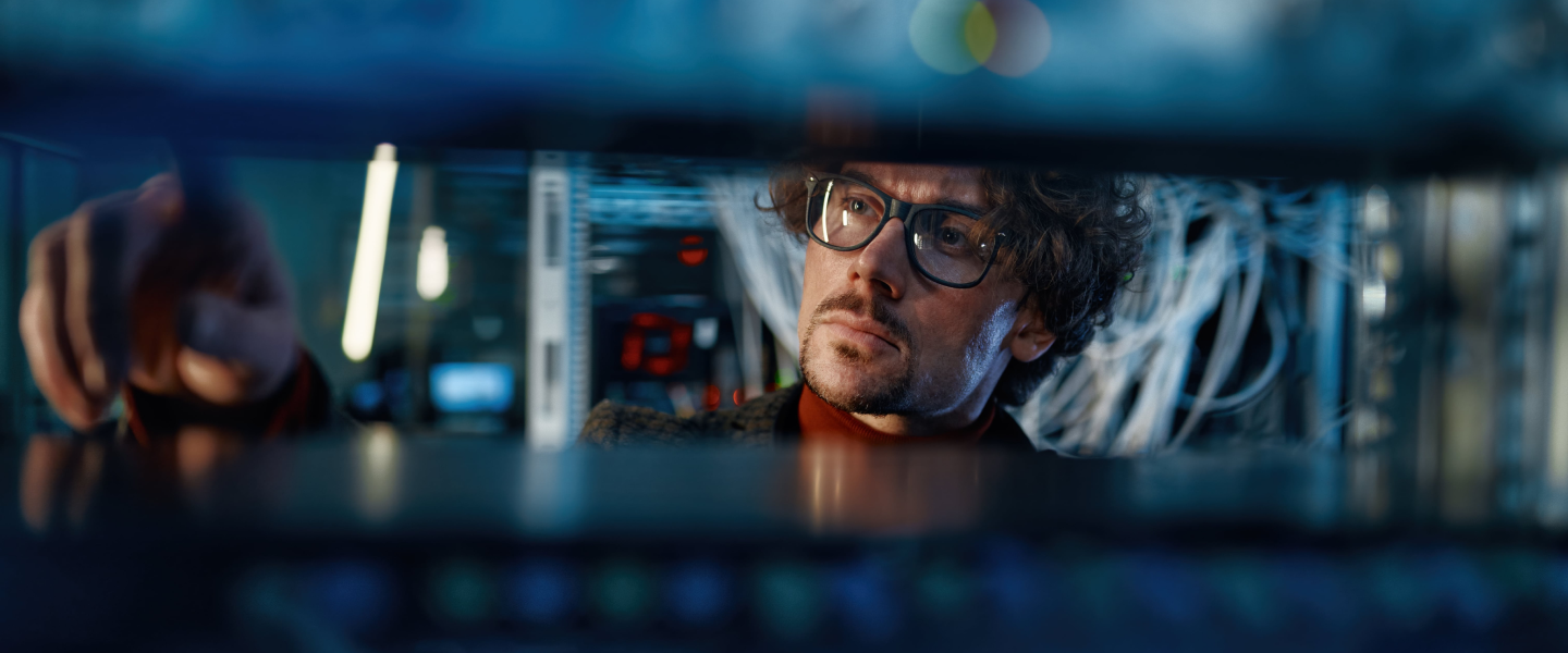 Man in glasses inspecting something computer related